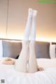 A woman laying on a bed with her legs up in the air.