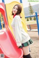 A woman in a school uniform standing next to a slide.