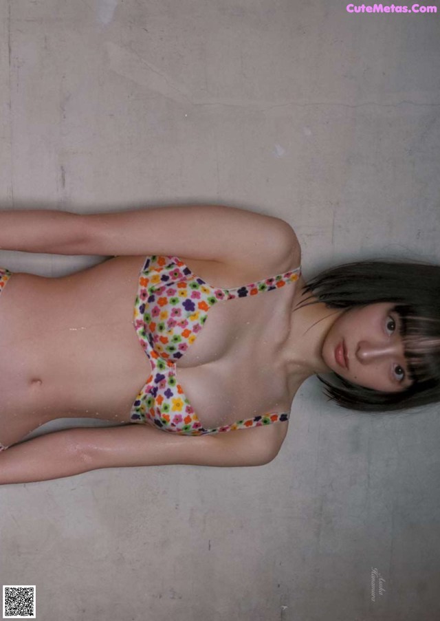 A woman in a bikini laying on the ground.