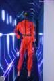 A mannequin wearing a red jumpsuit and a black mask.