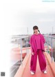 A woman in a pink outfit standing on a balcony.