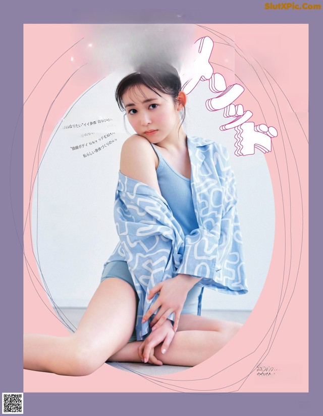 A woman sitting on the ground in front of a pink background.