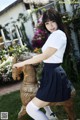 A woman in a school uniform riding a wooden horse.