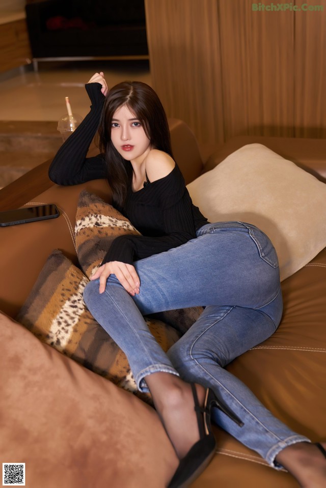 A woman sitting on a couch with her legs crossed.