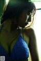 A woman in a blue bra looking out a window.