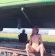 A naked woman sitting on a train track next to a man.