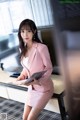 A woman in a pink suit sitting at a desk.