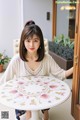 A woman sitting at a table in front of a door.