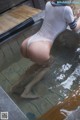 A woman in a white bodysuit sitting in a pool of water.